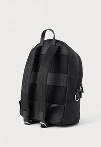 Musta reppu, jossa on pehmustettu verkkoselkä, säädettävät hihnat ja yläkahva. Ominaisuuksiin kuuluu tyylikäs, sileä materiaali, jossa on hienovaraisia korosteita.