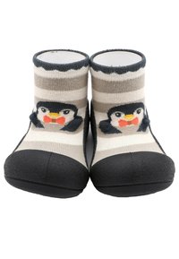 Calcetines con diseño de pingüino, con suelas de goma negra, parte superior de punto a rayas en beige y gris, que presentan un diseño de cara de pingüino en la parte delantera.