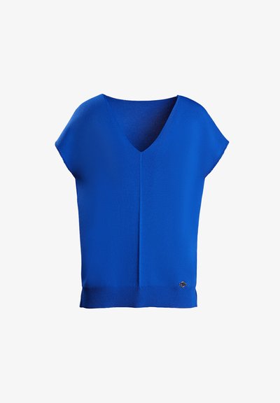 Kék V nyakú, rövid ujjú blúz, sima anyagból készült. Diszkrét függőleges varrás és díszítő emblémával a szegélyén.