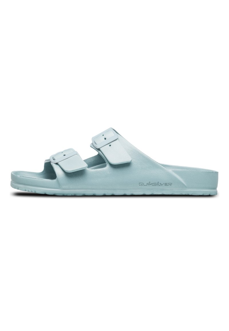 Sandales en plastique bleu clair avec deux sangles ajustables, semelle plate et semelle texturée. Marque visible sur le côté.