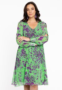 Grünes Kleid mit lila Leopardenmuster, V-Ausschnitt, langen transparenten Ärmeln und ausgestellt Rock. Verfügt über einen leichten, fließenden Stoff und eine lockere Passform.