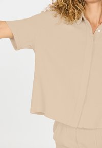 Beige shirt met korte mouwen, gemaakt van textuurstof, met een relaxte pasvorm en een button-down kraag, voorzien van een zichtbare knoopsluiting en een losse zoom.