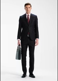 Mörk skräddarsydd kostym med notchslag, vit skjorta och en vinröd randig slips. Håller en grå läderportfölj, bär svarta skor.