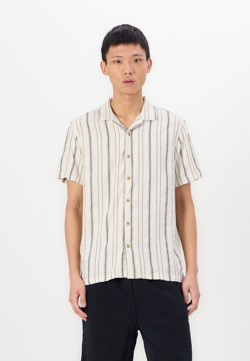 Camicetta a maniche corte, color crema con righe verticali blu, tessuto leggero, vestibilità rilassata, bottoni in legno naturale, design colletto aperto.