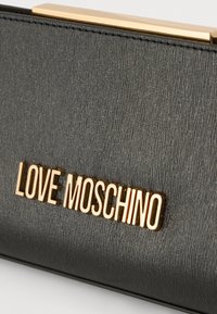 Μαύρο πορτοφόλι από δερματίνη με υφή, διακοσμημένο με μια χρυσή πλάκα λογότυπου "LOVE MOSCHINO". Κομψός σχεδιασμός με κούμπωμα και διακριτικές οριζόντιες γραμμές.