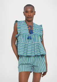 Completo con top e pantaloni a righe in verde, blu e viola. Presenta maniche arricciate, scollatura a V profonda con dettagli a frangia e un design peplum.
