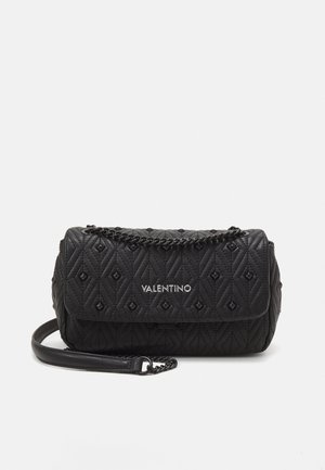 Sac à main matelassé noir Valentino avec motif losanges, logo argenté et bandoulière chaîne partiellement enroulée à l'avant sur un fond uni.