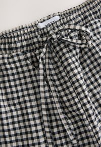 Zwart-witte geruite short met elastische tailleband en verstelbare trekkoord. Lichtgewicht stof met een licht gestructureerd uiterlijk.