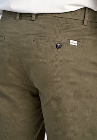 Olijfgroene, gestructureerde broeken met een subtiel patroon, voorzien van een achterzak, knoopsluiting en een label met de naam "Lindbergh."