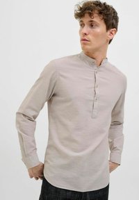 Langærmet beige skjorte med ståkrave, fem-knaps placket og manchetter. Fremstillet af tekstureret, let materiale.