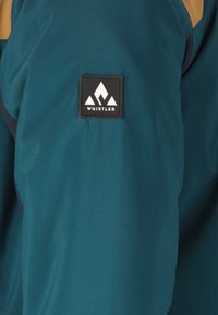 Teal jacket featuring a blend of materials with a smooth texture. Notable black logo patch with a white mountain design on the sleeve.