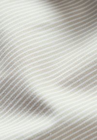 Tessuto texturizzato con strisce beige e crema alternate, caratterizzato da una superficie morbida e liscia e da una leggera lucentezza.