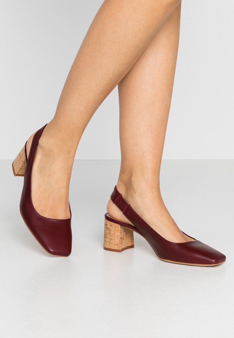 Chaussures slingback en cuir bordeaux avec un bout carré et un talon bloc en liège texturé, dotées d'un design échancré et d'une bride élastique pour le confort.