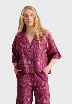 Kurzärmliges, knöpfbares Hemd und passende Hose im rosa-violetten Ikat-Muster, mit entspanntem Schnitt und weicher Textur.