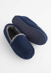 Marineblå fleece tøfler med grå kunstpelsforing, blød overdel, fletningsyning og tekstureret gummisål med bølge mønster.