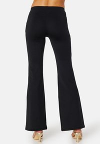 Pantaloni neri a palazzo realizzati in materiale elasticizzato, con un'alta vita e una texture liscia, dal design semplice.