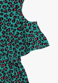 Ein türkises Kleid mit einem Tiermuster aus schwarzen und roten Punkten, kurzen, Rüschensleeves und einer gerafften Taille.