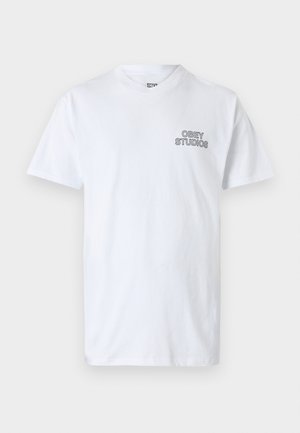 White cotton t-shirt featuring a round neckline and short sleeves, with "OBEY STUDIOS" printed in black on the left chest area.