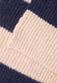 Uldstrik tæppe med skiftende navy blå og blød pink sektioner, med teksturerede striber og en hyggelig, fuzzy finish.