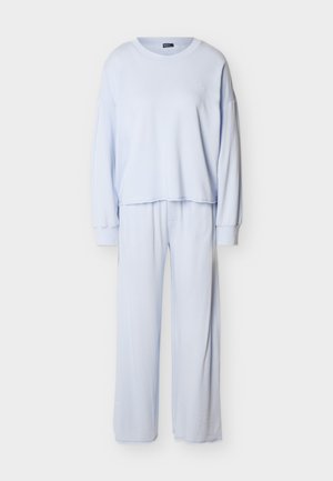 Ανοιχτό γαλάζιο μπλουζάκι με μακριά μανίκια και στρογγυλή λαιμόκοψη, συνδυασμένο με παντελόνι φαρδιάς γραμμής, από απαλό ύφασμα, σετ άνετης ένδυσης για χαλάρωση.