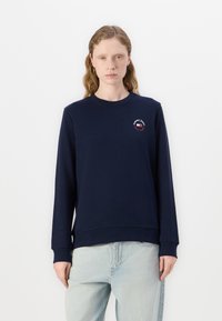 Sudadera azul marino hecha de una mezcla de algodón, cuenta con un escote redondo, mangas largas y un pequeño gráfico de logo en el pecho.