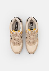 Baskets beiges et marron clair avec des accents tachetés noir et blanc, œillets jaunes, col rembourré et semelles intérieures de marque « mtng Comfort Foam ».
