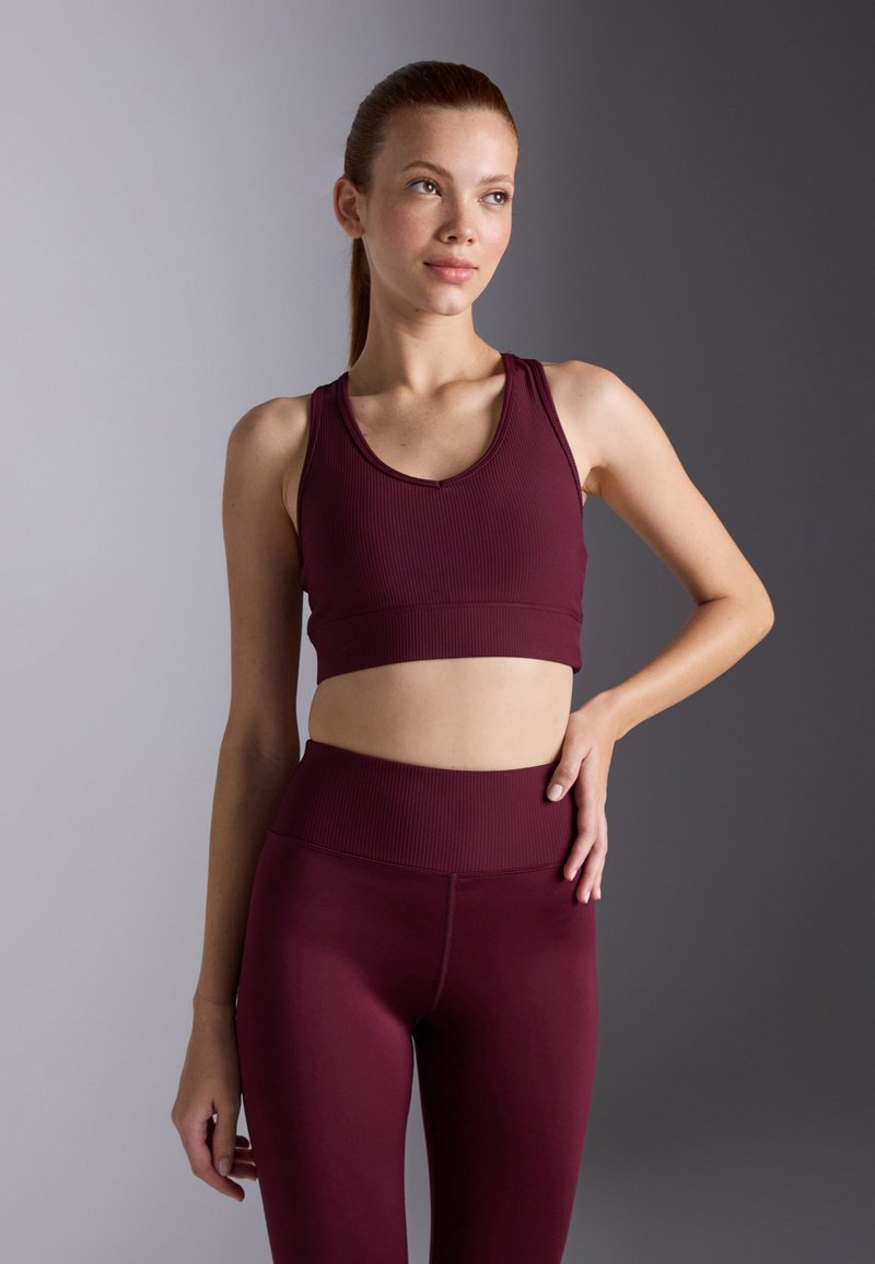 Bordeaux sports-BH og matchende høytalende leggings i ribbet stoff, med scoop-halsutringning og bredt midjebånd. Teksturert design.