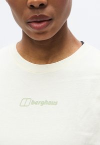 Ανοιχτό κρεμ T-shirt με στρογγυλή λαιμόκοψη, με διακριτικό πράσινο λογότυπο "berghaus" τυπωμένο στο μπροστινό μέρος. Υλικό από απαλό βαμβάκι.