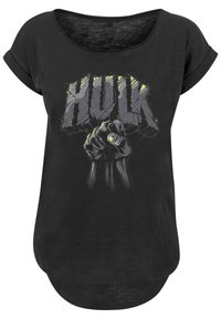 Melns T-krekls, kas rotāts ar attēlu ar sasprindzinātu dūri un vārdu "HULK" lieliem, treknraksta burtiem ar nolietotu tekstūru un zaļiem akcentiem.