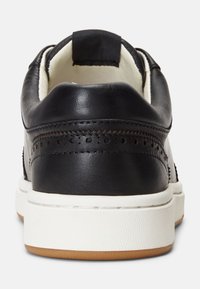 Black leather sneaker with a white rubber sole, featuring perforated detailing and a contrasting black heel tab.