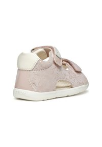 Sandalo in suede rosa chiaro con dettagli bianchi, due cinturini regolabili in Velcro e sezioni tagliate per la traspirabilità. Marchio Geox sul tallone.