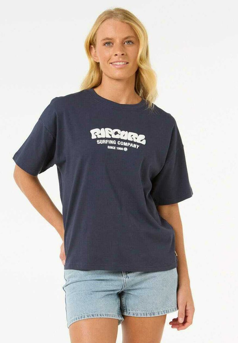 Camiseta de manga corta azul marino con el logo y el texto "Rip Curl" en blanco; material de algodón suave; corte relajado; combinada con pantalones cortos de mezclilla azul claros.
