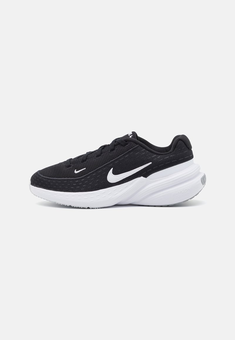 Black athletic shoes with a mesh upper and white accents. Features a cushioned sole, rounded toe, and textured side panels.