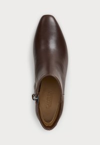 Bottine en cuir marron avec un bout pointu, fermeture éclair sur le côté et une texture lisse ; présente un logo en relief subtil à l'intérieur.