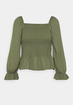 Blouse à manches longues vert olive avec corsage smocké, encolure carrée, épaules bouffantes, et poignets et ourlet volantés.
