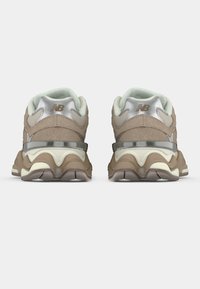  smešasti smeđi i bež tenisice sa antilop i mrežnim panelima, metalik srebrnim detaljima i valovitom dizajnom potplata. Vidljiv logo na peti.