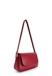Piccola borsa a tracolla in pelle rossa con chiusura a pattina e sottile cinturino, esposta su sfondo bianco.