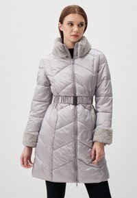 Giacca puffer grigia chiara con vita rifinita da una cintura, colletto e polsini in pelliccia sintetica, texture a rombi e chiusura frontale a zip completa.