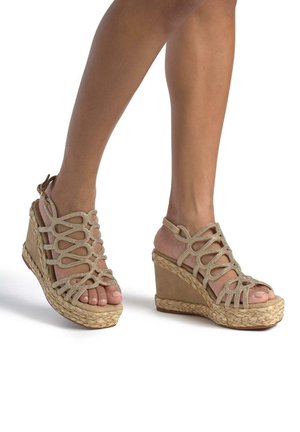 Sandali con zeppa beige, caratterizzati da una suola in corda intrecciata, cinturini intrecciati e dettagli in strass. Design con punta aperta e cinturino alla caviglia.