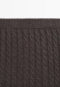 Tissu tricoté gris foncé avec motif câblé vertical et taille côtelée sur le bord supérieur.