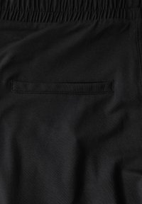 Zwarte elastische taillebandbroeken met een strakke, gladde textuur, featuring een discrete platte achterzak en minimale stikseldetails.