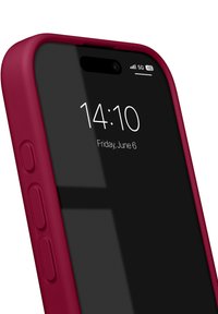 Smarttelefon med svart skjerm i en vinrød silikonetui. Har volumknapper på siden og 5G-signalindikator.