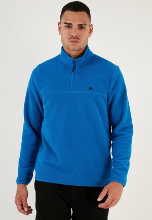 Blauer Fleece-Pullover mit hohem Kragen, halblangem Reißverschluss und kleinem schwarzen Logo. Weicher Stoff mit langen Ärmeln und entspanntem Schnitt.