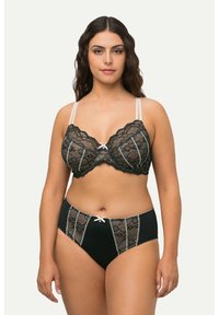 Zwarte kanten beha en bijpassende high-waisted slip met beige accenten, voorzien van decoratieve strikken en een doorschijnende textuur met verticale kanten panelen.