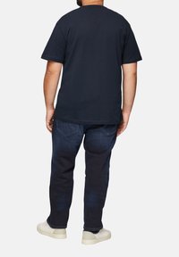 Navyblauwe katoenen t-shirt met korte mouwen, gecombineerd met een donkere spijkerbroeken. Casual pasvorm, simpele uitstraling, geen zichtbare logo's of patronen.