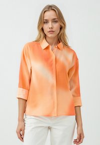 Button-up Hemd aus leichtem, glattem Stoff mit einem Farbverlauf von hellorange zu dunklerem Orange, mit aufrollbaren Ärmeln und einem Kragen.