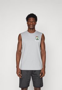 Pilkas be rankovių marškinėlis su Bostono Celtics logotipu kairėje krūtinės pusėje, derinamas su juodomis tekstūruotomis šortais su tinklinio raštu.
