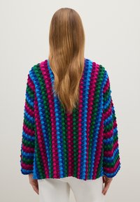 Cárdigan de punto multicolor con textura de bolitas en relieve en franjas de rosa, verde, azul y morado. Corte holgado y relajado con mangas largas.