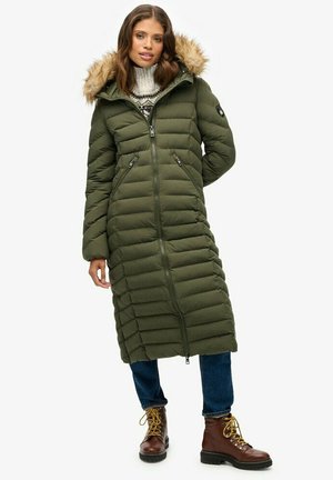 Manteau long en duvet vert olive avec des coutures horizontales, capuche amovible en fourrure, deux poches zippées et une fermeture éclair frontale sur toute la longueur.