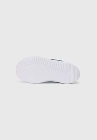 Semelle de basket blanche avec des motifs en vagues texturés, des bords lisses et une forme arrondie. La semelle présente un relief pour une meilleure adhérence.